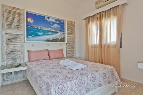 1 dormitorio con 1 cama con una pintura en la pared en Aperanto Apartments, en Karpathos