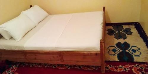 a bed with a white pillow and a rug at Maison D'hote Amazir in Boumalne