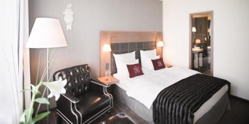 a hotel room with a bed and a chair at Mövenpick Hotel Stuttgart Airport in Stuttgart