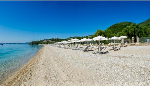 a beach with chairs and umbrellas and the water at Villa Renata Gold in Barbati
