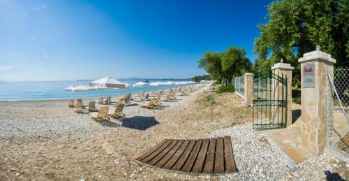 a beach with chairs and a fence and the ocean at Villa Renata Gold in Barbati