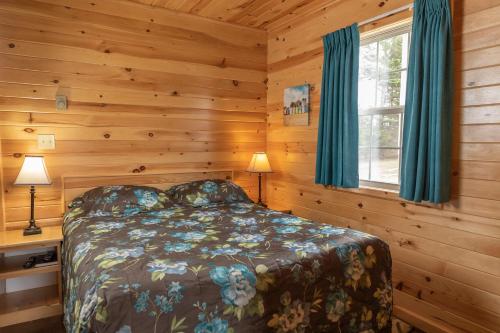 a bedroom with a bed in a log cabin at Fairways Cottages in Cavendish