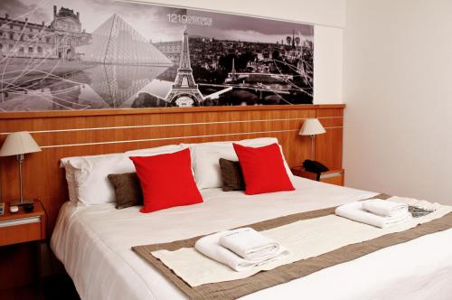 1 dormitorio con 1 cama grande con almohadas rojas en Catamarca Suites Land en Rosario