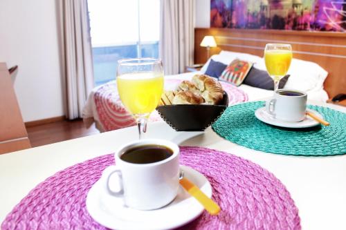 a table with a cup of coffee and a glass of orange juice at Catamarca Suites Land in Rosario