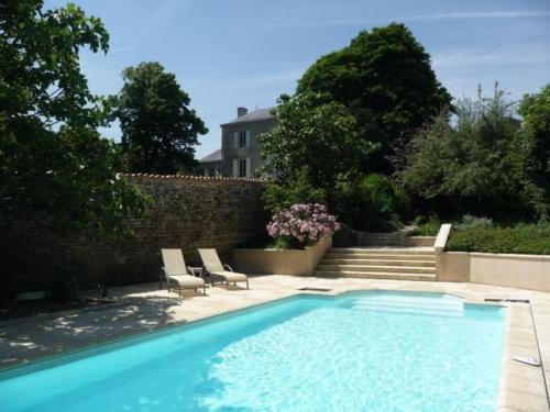une piscine avec des chaises et une maison en arrière-plan dans l'établissement Coté Marais - gite familial, à Chaillé-les-Marais
