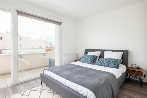 1 dormitorio con cama y ventana grande en Appartement de standing avec grande terrasse en Villeurbanne