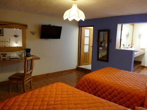 a hotel room with two beds and a television at El Meson de los Poetas in Guanajuato