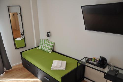 a room with a green chair and a flat screen tv at EVA LUXURY ROOMS CAGLIARI in Cagliari
