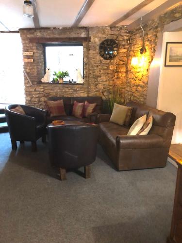 a living room with a leather couch and chairs at The George at Nunney in Frome