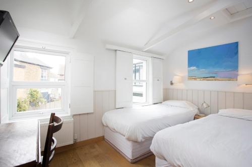 two beds in a white room with two windows at Hotel Continental in Whitstable