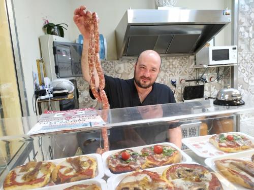 a man standing behind a counter with a large piece of meat at Aspra al delfino blu in Bagheria