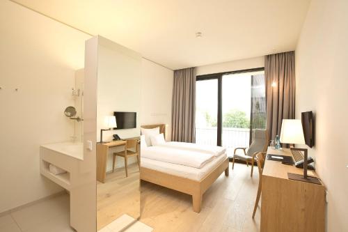 a hotel room with a bed and a desk with a computer at Hotel Kloster Haydau in Morschen