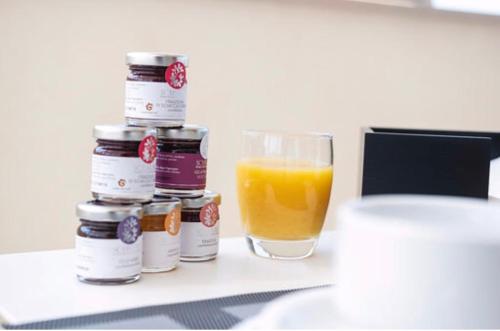a glass of orange juice next to a stack of jam jars at Imera B&B in Favignana