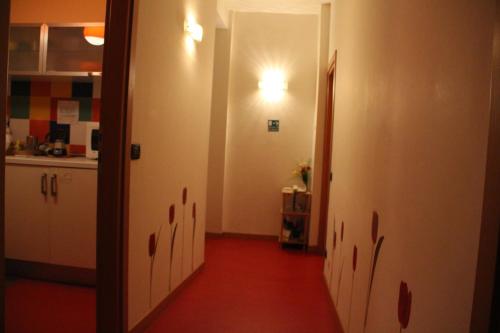 a kitchen with a hallway with a red floor at ARCOBALENO AFFITTACAMERE in Verona