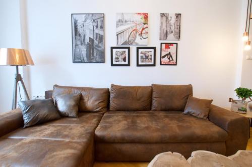 a brown leather couch in a living room with pictures on the wall at Standard Apartment by Hi5 - Madách Imre 1 in Budapest