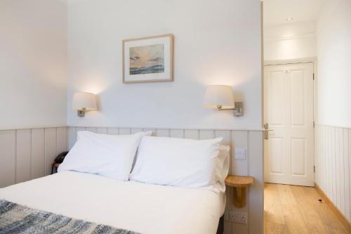 a bedroom with a white bed with two lamps at Hotel Continental in Whitstable