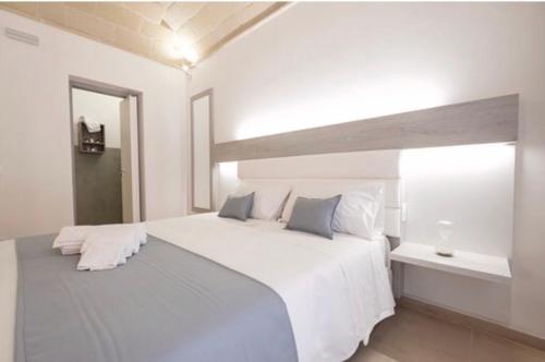 a white bedroom with a large white bed and a window at Imera B&B in Favignana