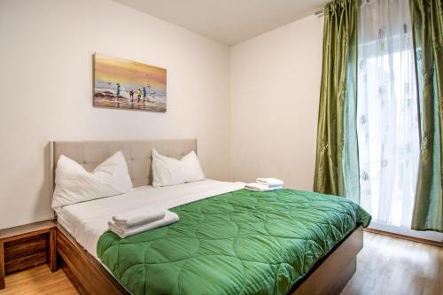 a bedroom with a bed with a green blanket at Apartments Mijo in Dugi Rat