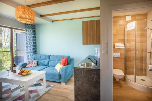 a living room with a blue couch and a bathroom at Apartamenty Klifowa z widokiem na morze in Trzęsacz