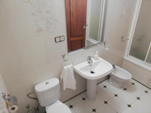 a white bathroom with a toilet and a sink at Piso Tarayuela in Barbate