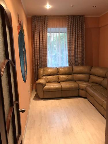 a living room with a brown couch and a window at DAUGAVPILS in Daugavpils