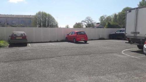 une voiture rouge garée dans un parking à côté d'une clôture dans l'établissement Talence, studio cosy 27 M2, Bordeaux 10 mn en tram, à Talence