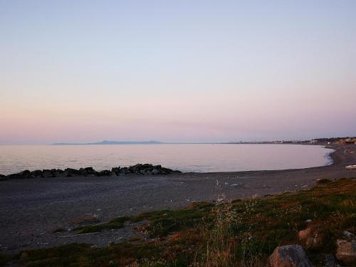 a beach with rocks in the water at sunset at B&B Tonnarella Beach in Torre Forte