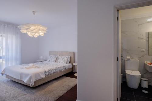 ein weißes Schlafzimmer mit einem Bett und einem Badezimmer in der Unterkunft Music House 3 bedroom Apt w garage in Porto
