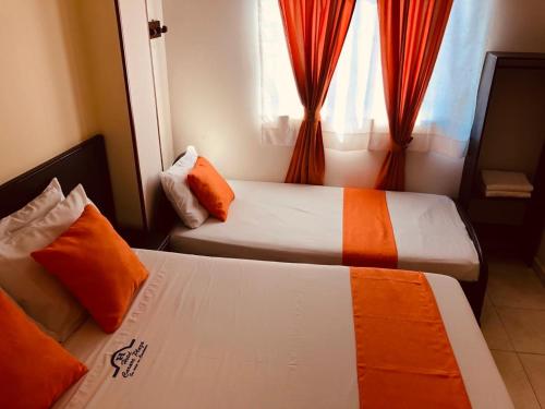 two beds in a hotel room with a window at Hotel Carare Plaza in Cimitarra