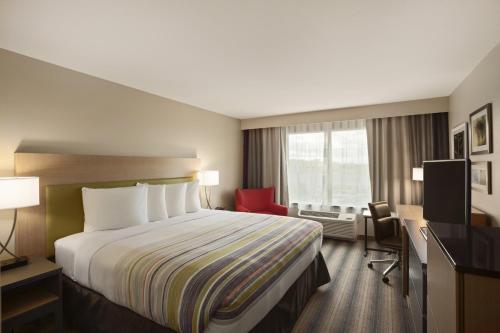 a hotel room with a bed and a red chair at Country Inn & Suites by Radisson, Bradenton-Lakewood-Ranch, FL in Bradenton