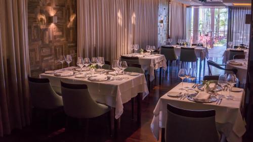 a dining room with tables and chairs with wine glasses at Vogal Luxury Beach Hotel & SPA in Natal
