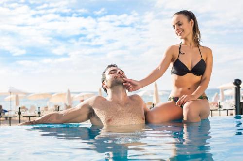 a man and a woman sitting in the swimming pool at Playa Los Arcos Hotel Beach Resort & Spa in Puerto Vallarta