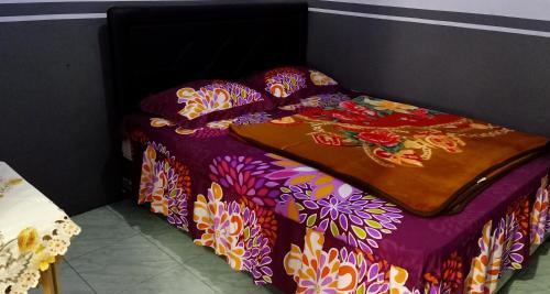 a bed with a purple comforter with flowers on it at Holiday Home Anggun Bromo in Bromo