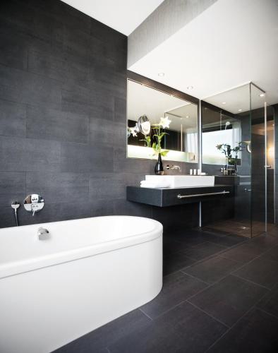 a bathroom with a tub and a sink and a mirror at Mövenpick Hotel Stuttgart Airport in Stuttgart