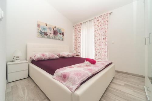 - une chambre blanche avec un lit et une couverture violette dans l'établissement Mia, à Baška Voda