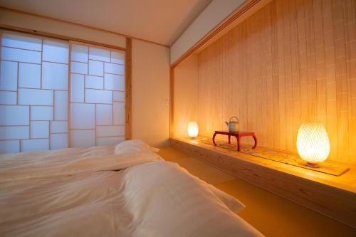 a bedroom with a bed and a table with a lamp at Oyado Den Rikyu in Yufuin