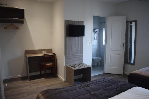 a hotel room with a bed and a desk and a television at Hotel Puy De Dôme in Paris
