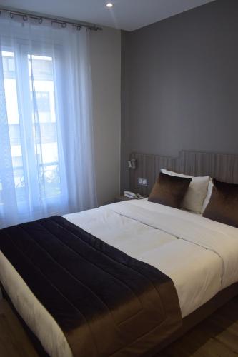 a bedroom with a large bed with a large window at Hotel Puy De Dôme in Paris