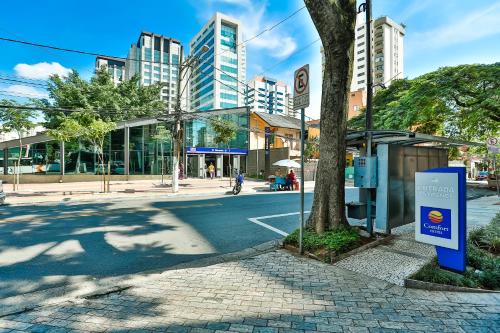 a city street with a tree and a bus stop at Comfort Ibirapuera in Sao Paulo
