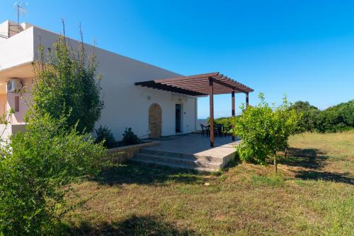 a house with a wooden pergola next to a field at Naiada Stomio-A apartment in Filiatra