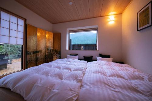 a large white bed in a bedroom with a window at Oyado Den Rikyu in Yufuin