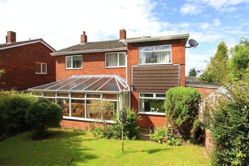 a brick house with a greenhouse in a yard at Beautiful and Peaceful village location in Bishop's Wood