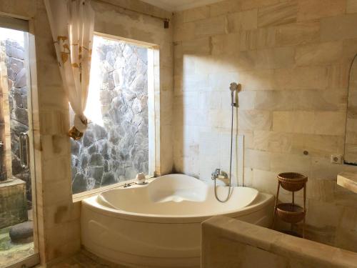 een badkamer met een bad en een raam bij Bale Asri Bukit Jimbaran in Jimbaran