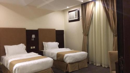 Habitación de hotel con 2 camas y ventana en Dar Telal Hotel suites en Abha