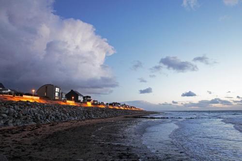 una playa con un muro de roca y el océano en Hôtel Les Coutainvillaises, en Agon-Coutainville