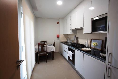 a kitchen with white cabinets and a table in the distance at Quinta das Perdizes - Premium in Ponta Delgada