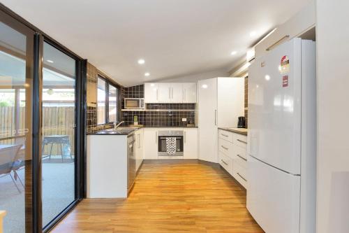 a kitchen with white cabinets and a refrigerator at North Central Holiday Home in North Mackay