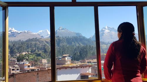 a woman looking out of a window at the mountains at Morales Guest House in Huaraz