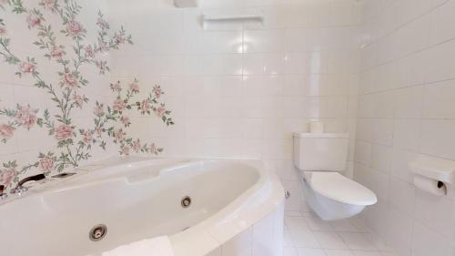 a white bathroom with a tub and a toilet at Caspar Badrutt - St. Moritz in St. Moritz