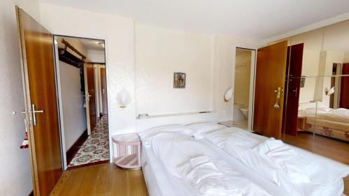 a large white bed in a room with a mirror at Caspar Badrutt - St. Moritz in St. Moritz